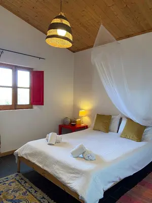 a bedroom with a bed with a mosquito net at Casa Pedralva in Vila do Bispo