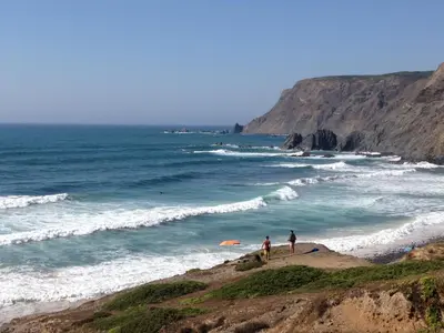 two people standing on a beach near the ocean at Casa Pedralva in Vila do Bispo
