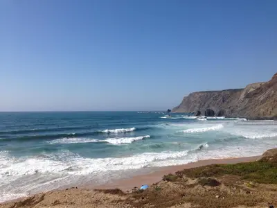a beach with a bunch of waves in the ocean at Casa Pedralva in Vila do Bispo