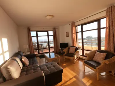 a living room with a couch and chairs and windows at Marina Club Apartment in Funchal