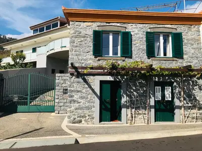 a stone house with green shutters and a green door at Casa do Lugar da Ribeira in Ribeira Brava
