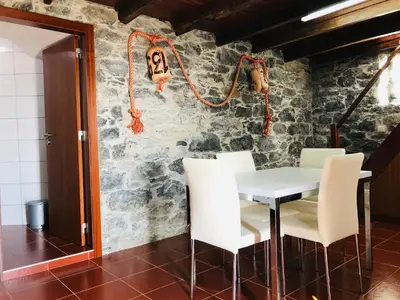 a dining room with a table and white chairs at Casa do Lugar da Ribeira in Ribeira Brava