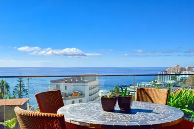 a table on a balcony with a view of the ocean at Seculo XXI-U, a Home in Madeira in Funchal