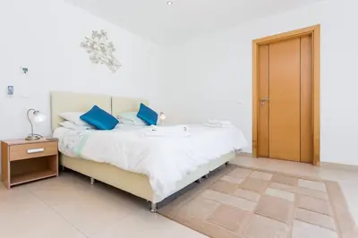 a white bedroom with a bed with blue pillows at CoolHouses Algarve, Casa Redonda, V3 Lagos in Lagos