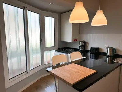 a kitchen with a counter with two chairs and two windows at Cozy Duplex Retreat by Green Park & Ocean View in Funchal