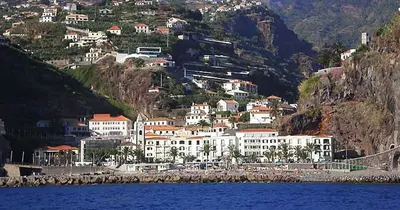 a group of buildings on a hill next to the water at Casa Alto Santo António in Ponta do Sol