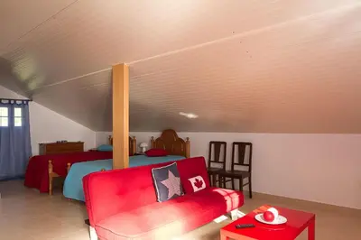 a bedroom with a bed and a red couch at Casa Alto Santo António in Ponta do Sol