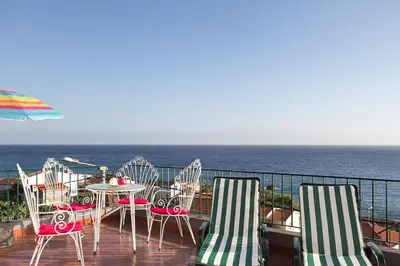 a balcony with chairs and a table and the ocean at Casa Alto Santo António in Ponta do Sol