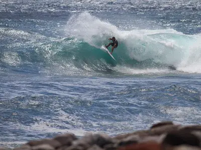 a man riding a wave on a surfboard in the ocean at Casa Alto Santo António in Ponta do Sol