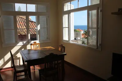 a dining room with a table and two windows at Casa da Fininha in Calheta