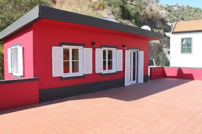 a red house with white windows and a roof at Casa da Fininha in Calheta