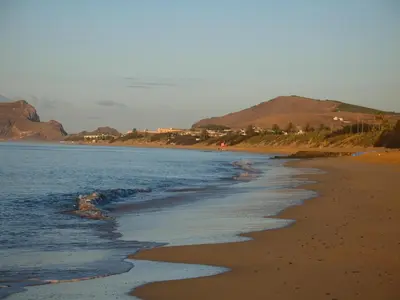 a beach with the ocean and mountains in the background at Villa Ines, at the beach in Porto Santo