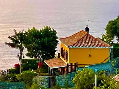 a yellow church with a cross on top of it at CASA DOS FALCÕES casa rural de construção tradicional in Fajã da Ovelha