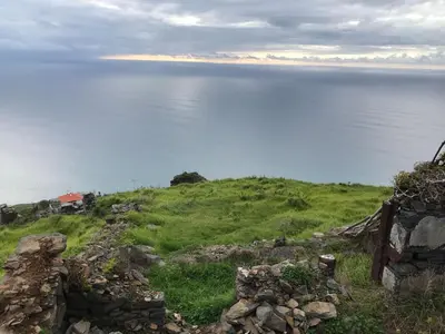 a grassy hill with the ocean in the background at CASA DOS FALCÕES casa rural de construção tradicional in Fajã da Ovelha