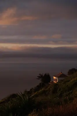 a house on top of a hill with the ocean at CASA DOS FALCÕES casa rural de construção tradicional in Fajã da Ovelha
