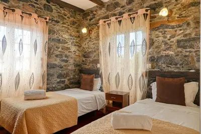 a bedroom with two beds and two windows at Casa do Pombal, a Home in Madeira in Arco da Calheta
