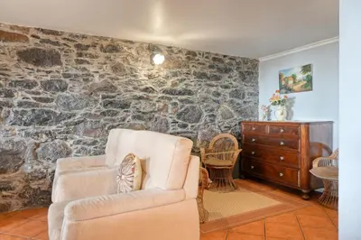a living room with a couch and a stone wall at Casa do Pombal, a Home in Madeira in Arco da Calheta
