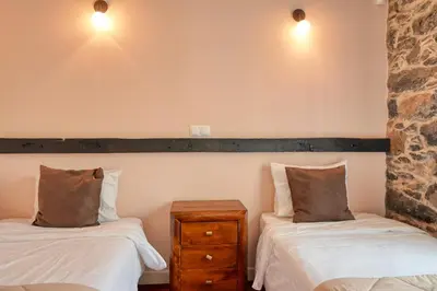 a bedroom with two beds and a nightstand and lights at Casa do Pombal, a Home in Madeira in Arco da Calheta