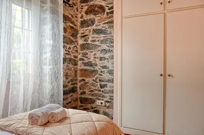 a bedroom with a bed and a stone wall at Casa do Pombal, a Home in Madeira in Arco da Calheta