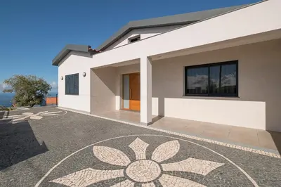 a bedroom with a large bed with a large window at Villa Guiné in Arco da Calheta