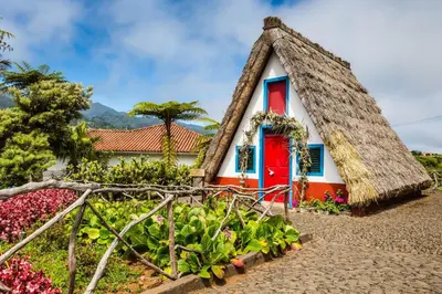 a thatch roof house with a red door at Central Suite in Funchal 1N in Funchal
