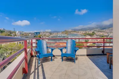 a balcony with two blue chairs and a table at Funchal Marina Bay in Funchal
