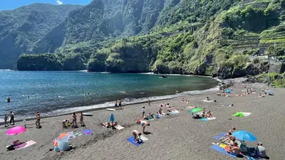 a group of people on a beach with umbrellas at Porto Moniz Villa in Porto Moniz