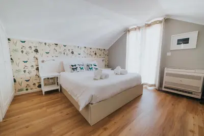 a bedroom with a large white bed and wooden floors at Mansarda dos Aranhas by Madeira Best Apartments in Funchal