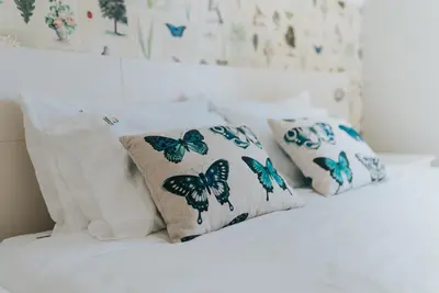 a white bed with blue butterflies pillows on it at Mansarda dos Aranhas by Madeira Best Apartments in Funchal