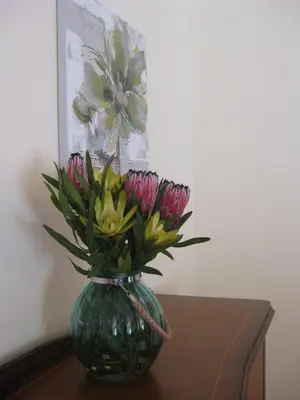 a green vase filled with flowers on a table at Casa Maresia- Sea view & Private pool in Ponta do Sol