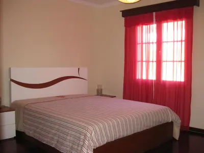 a bedroom with a bed and a window with red curtains at Casa Maresia- Sea view & Private pool in Ponta do Sol