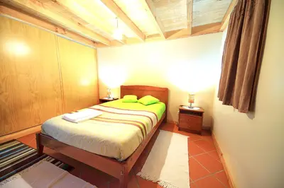 a small bedroom with a bed with green pillows at Charming Studio with Sea View - Ponta do Pargo - 20 m² in Ponta do Pargo