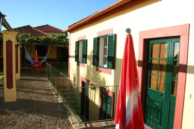 a building with green doors and red umbrellas on it at Charming Studio with Sea View - Ponta do Pargo - 20 m² in Ponta do Pargo