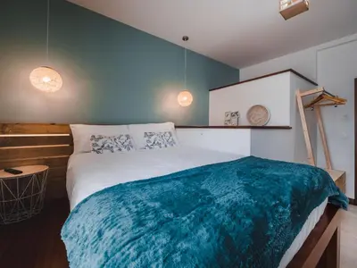 a bedroom with a large bed with a blue blanket at Ohana Madeira Guest House in Porto da Cruz