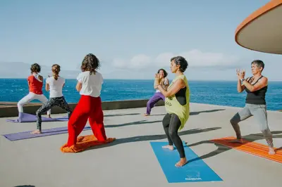 a group of people in a yoga class by the ocean at Ohana Madeira Guest House in Porto da Cruz