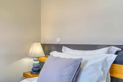 a bedroom with a bed with white sheets and a lamp at Vilamar- Madeira Inn Group in Calheta