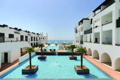 a swimming pool with palm trees in a building at Belmar Spa & Beach Resort in Lagos