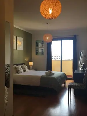 a bedroom with a bed and a window and two lights at Atlantis Apartment in Câmara de Lobos