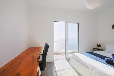 a white bedroom with a bed and a large window at Casa Serena Apartments in Arco da Calheta