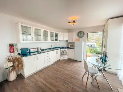 a kitchen with white cabinets and a glass table at Casa Serena Apartments in Arco da Calheta