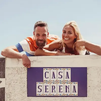 a man and a woman are standing behind a sign at Casa Serena Apartments in Arco da Calheta
