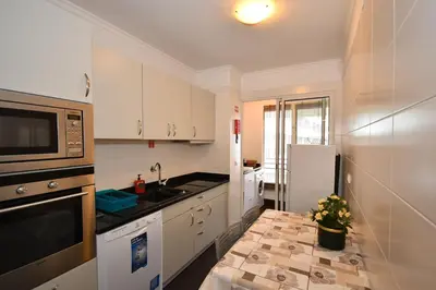 a kitchen with white cabinets and a sink and a refrigerator at M Palace II in Funchal