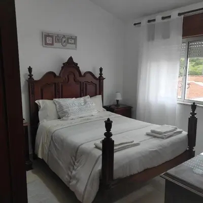 a bedroom with a large bed with a wooden headboard at Casa Furt@do in Burgau