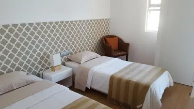 a hotel room with two beds and a chair at Apartamento Funchal com vista Mar in Funchal