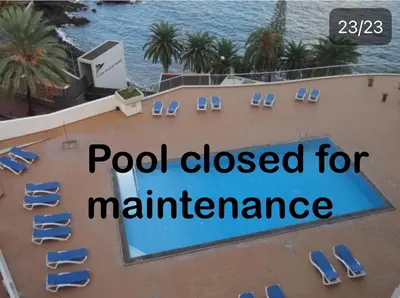 a sign on a building with chairs and a swimming pool at Apartamento Funchal com vista Mar in Funchal