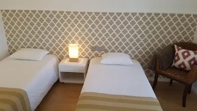a small room with two beds and a chair at Apartamento Funchal com vista Mar in Funchal