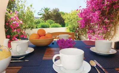 a table with cups and a bowl of oranges on it at Buganvilia Praia da Luz in Luz