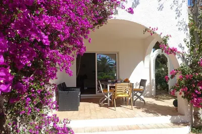 a patio with purple flowers and a table and chairs at Buganvilia Praia da Luz in Luz