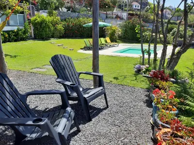 two chairs sitting next to a yard with a pool at Casa Velha D Fernando e Casa Avó Augusta in Ribeira Brava