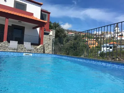 a large swimming pool in front of a house at Vila do Rocha in Calheta